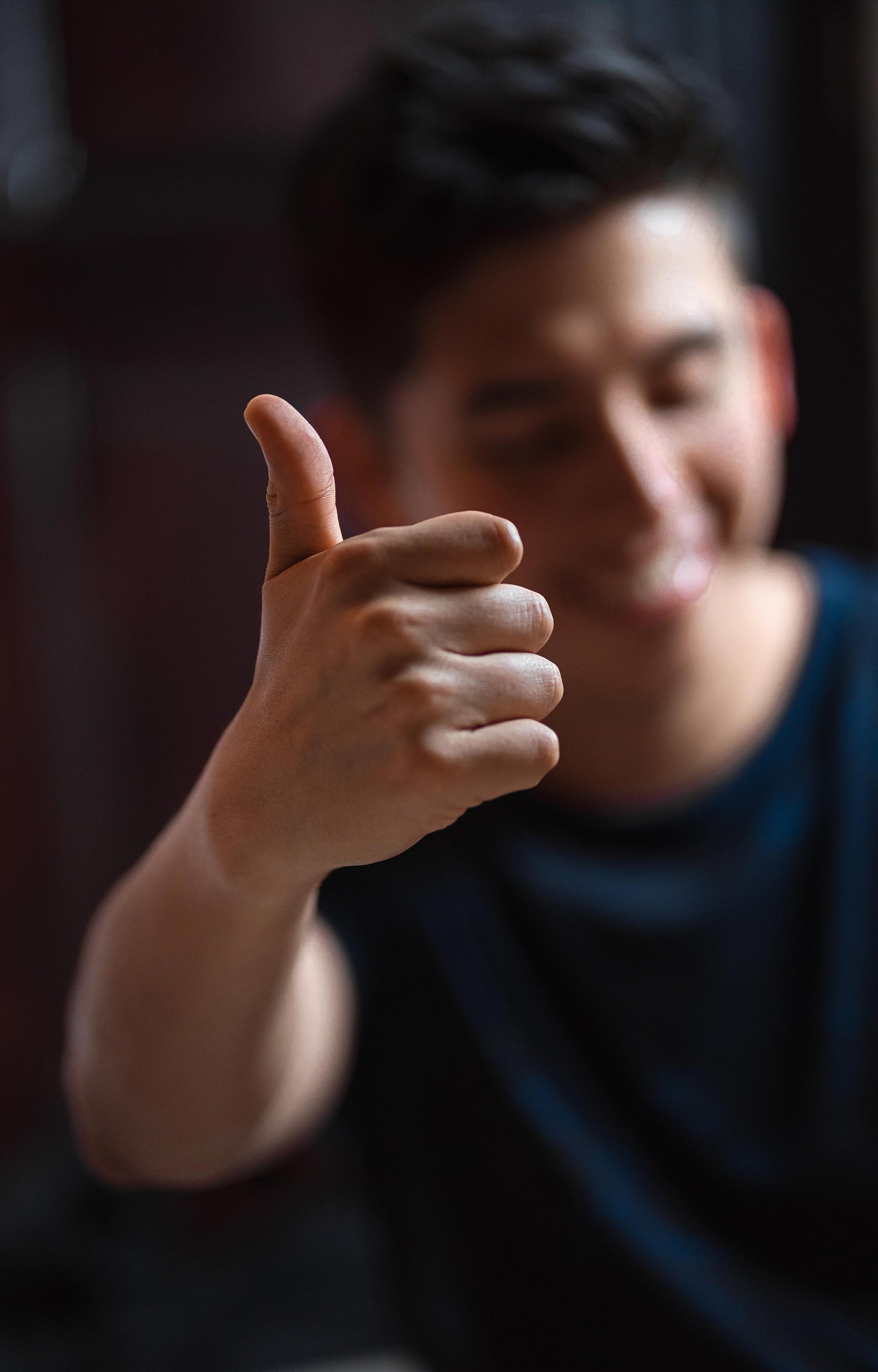 A man makes the thumbs-up sign, which expresses his positive attitude and support